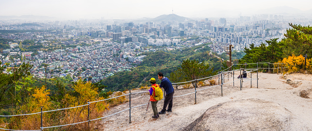 Hikers on top of Inwangsan mountain peak looking out over the crowded cityscape of Seoul, South Korea’s vibrant capital city.