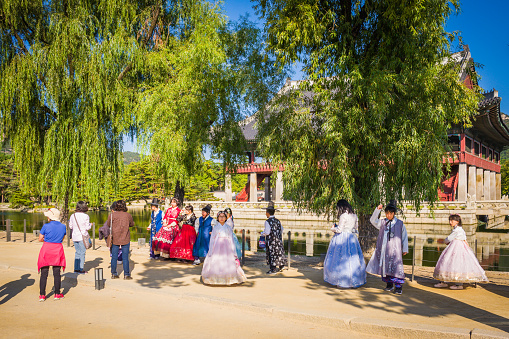 Crowds of tourists taking pictures with traditional Korean dress outside Gyeongbokgung pavilion in Seoul, South Korea.