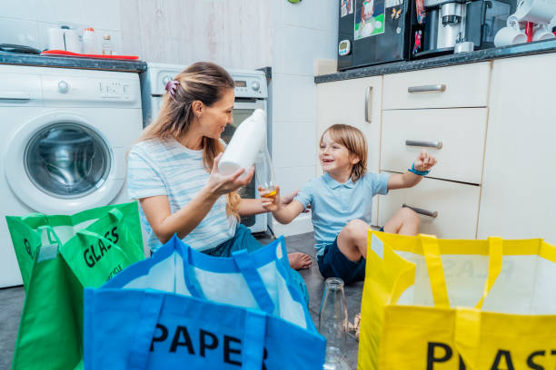 istock Mother using game is teaching kid how to recycle help the boy aware environmental importance - mom educates son sort garbage into different bins on kitchen. Family sorting garbage at home. recycling 1481204721