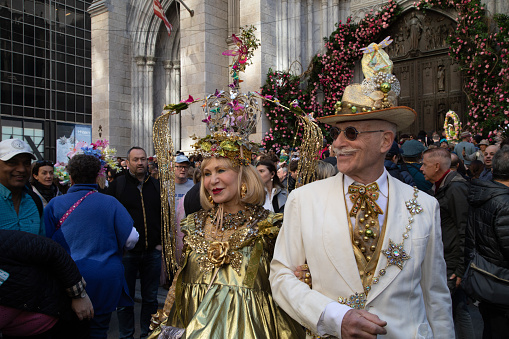 A couple in coordinating, elaborate gold costumes pose for pictures during the Easter Bonnet Parade in New York City.