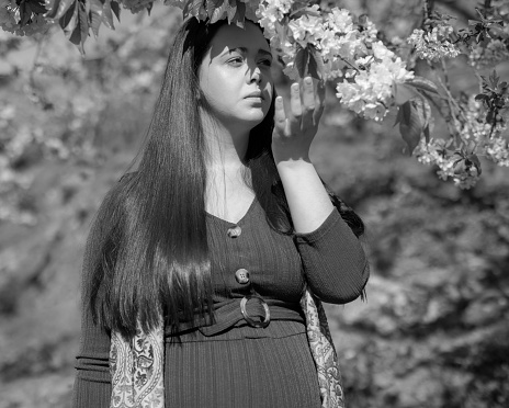 Pregnant young woman among cherry trees.