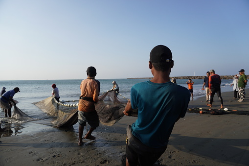 Fishermen pull their net on a beach in Banda Aceh on March 07, 2023