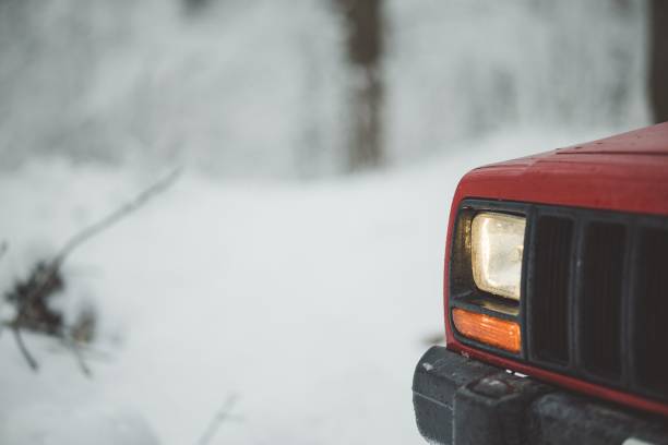 A lonely SUV covered in the snow at night, during a blizzard, illuminated just by one street light