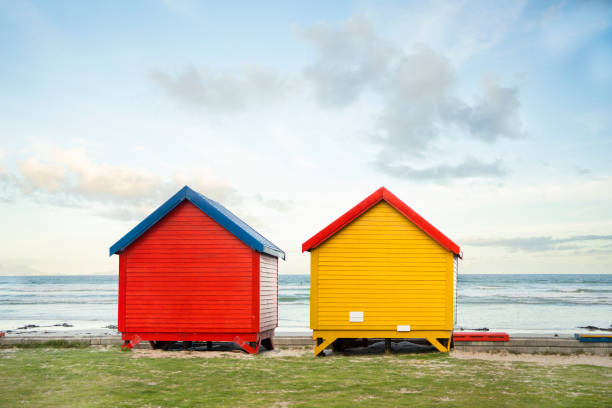Two bright red and yellow beach huts standing side by side on a beach on a late afternoon in the summertime