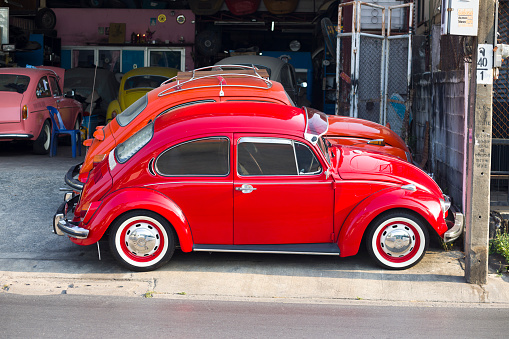 Parked red Volkswagen oldtimers outside of small auto repair shop for restauration of oldtimers in Bangkok Ladprao