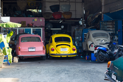 Several parked Volkswagen oldtimers at small auto repair shop for restauration of oldtimers in Bangkok Ladprao