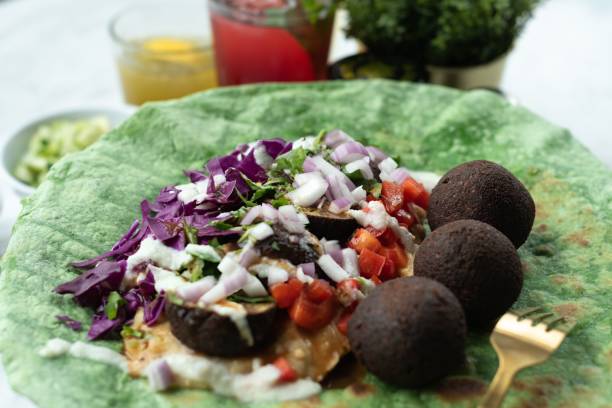 Close-up shot of ingredients for tortilla falafel wrap, with diced tomatoes, onions, jalapenos