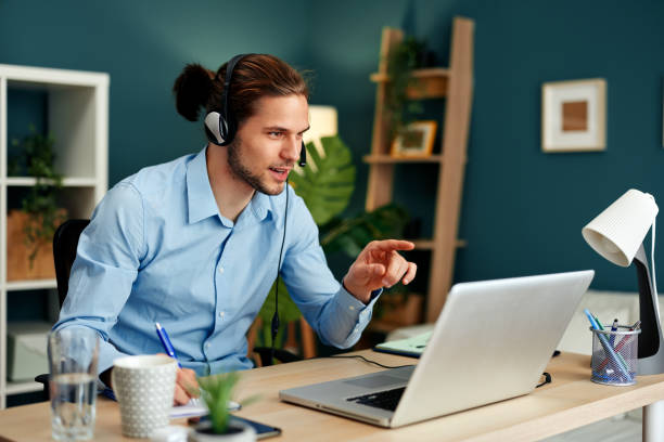 istock Young man with a headset and a laptop has a conference call in the office 1481221068