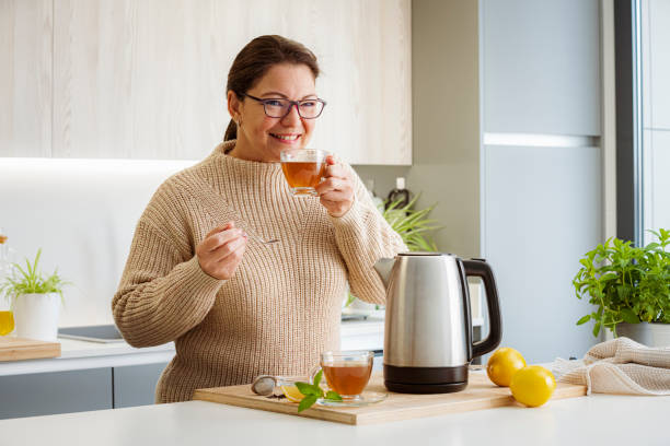 Happy woman enjoying hot tea in kitchen