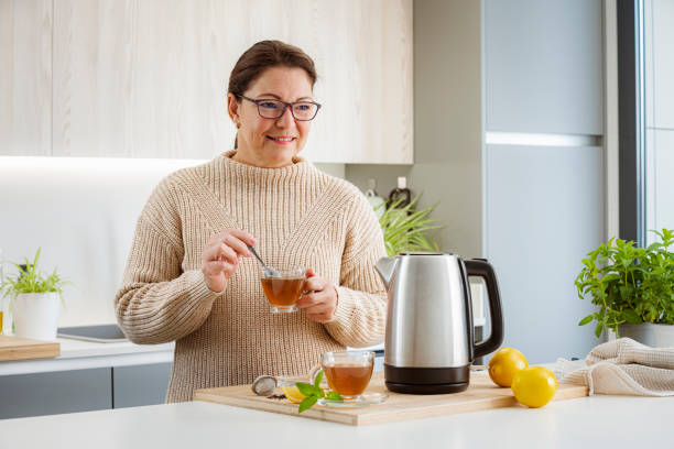istock Woman holding a cup of hot tea in kitchen 1481221352