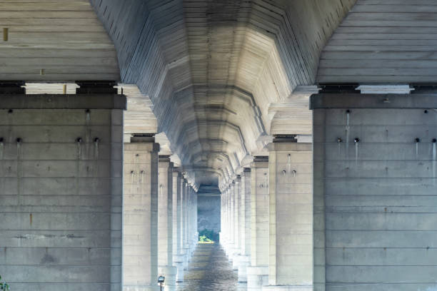 Tunnel from column under road bridge in city. Row pillars and group arches.
