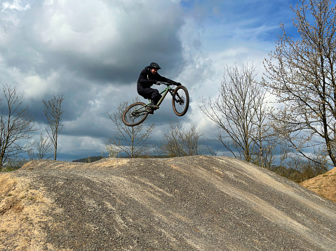 A mountain biker hits one of the GLC drops in Whistler, BC. He pushes the bike sideways as he launches of the drop.