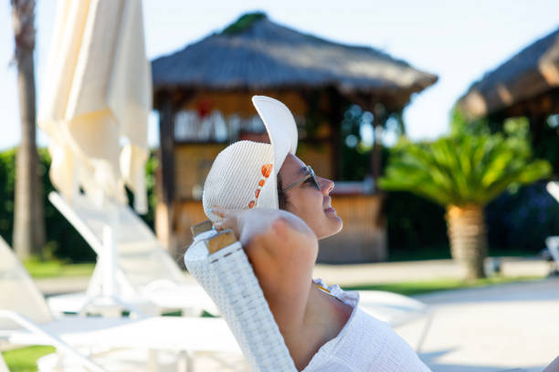 Smiling young woman lying back in a poolside lounge chair