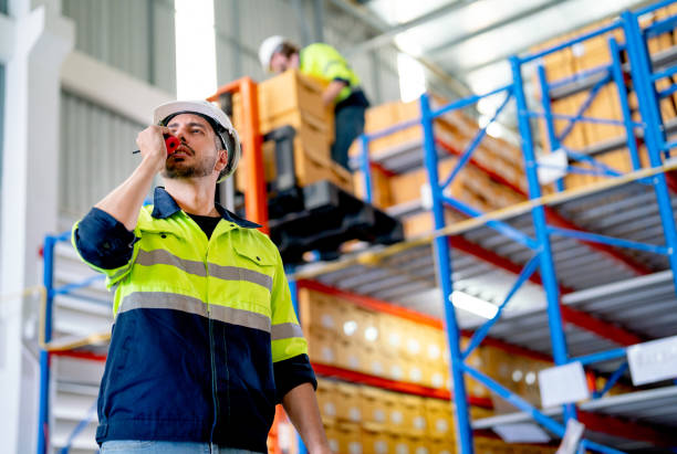 istock Smart professional warehouse worker use walkie-talkie to contact his co-worker during other worker still carry box or work in the background. 1481226637