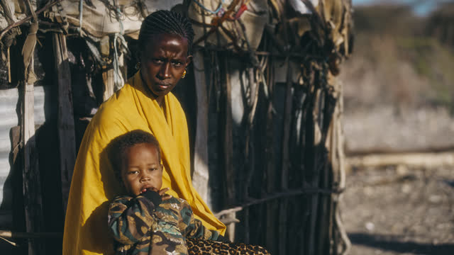 SLO MO Mother with a child sits in front of her tribal hut and looks to the camera - Samburu tribe