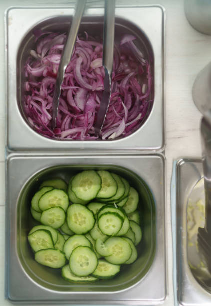 istock Sliced fresh cucumbers and red onions in containers, shot directly from above on a kitchen counter 1481233779