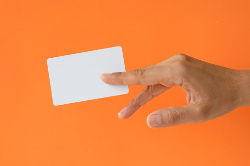 Close-up of a card in a woman's hand isolated on orange.