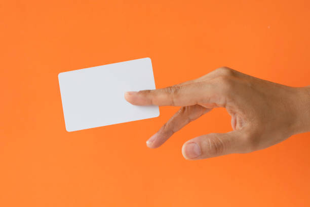Giving A card Close-up of a card in a woman's hand isolated on orange. gift vouchers stock pictures, royalty-free photos & images