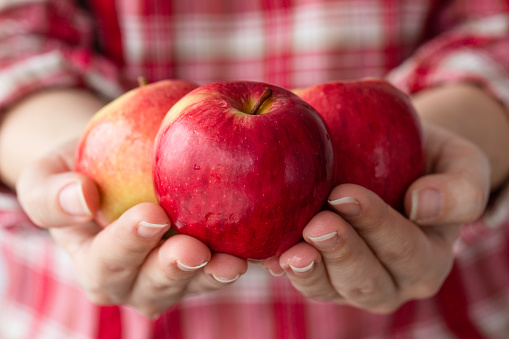 Young woman holding red apples.