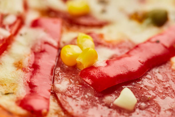Freshly baked tasty pepperoni pizza with salami, mozzarella cheese, corn and pepper served on wooden background with tomatoes, sauce and herbs. Food delivery concept. Restaurant menu