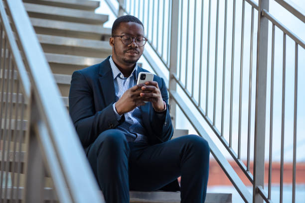 istock Serious African-American young man using smart phone on the stairs 1481239487