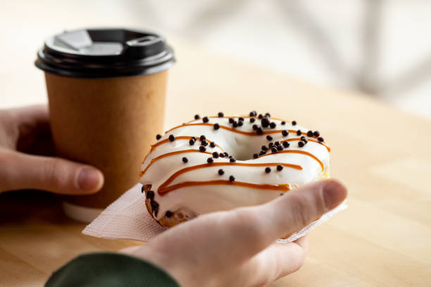 Appetizing donut and coffee in male hands, close-up.