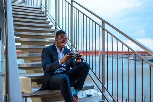Young African-American businessmen using a smart phone outdoors and watching online content