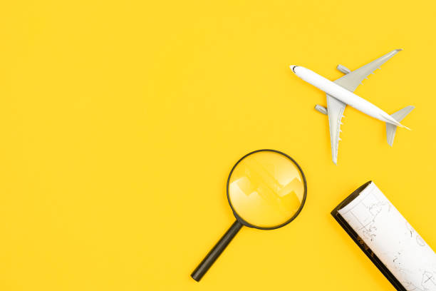 istock Airplane model, map and magnifier on yellow background, flat lay. 1481240793