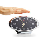 Hand reaching out to push the sneeze button on vintage alarm clock