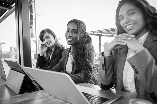 Three smiling businesswomen work with their computers, black and white photo.