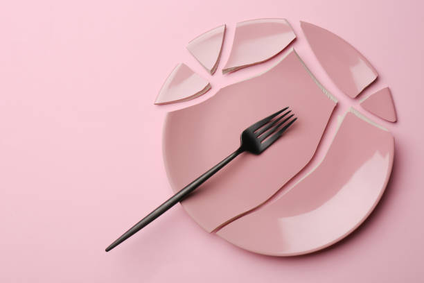 istock Pieces of broken ceramic plate and fork on pink background, flat lay. Space for text 1481247202