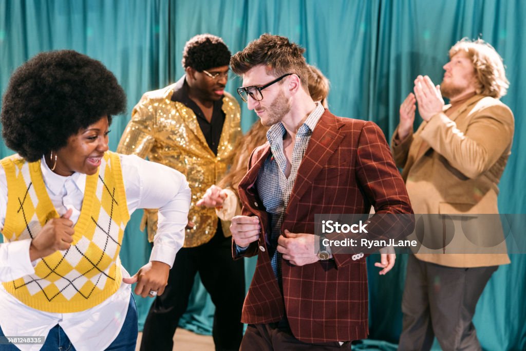 Retro Dance Party A group of friends in late 1970's or early 1980's style and fashion dance together in a live television studio setting. Party - Social Event Stock Photo