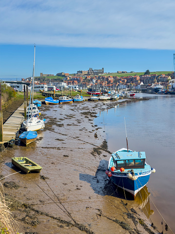 Whitby Abbey sits above Whitby Harbour at low tide. 8th April 2023.