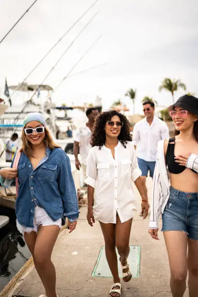 Photo of Group of friends arriving to the harbor to enter a yacht