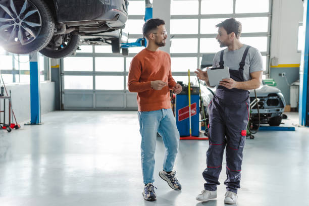 cliente y técnico de automoción hablando en un taller - customer auto repair shop car mechanic fotografías e imágenes de stock