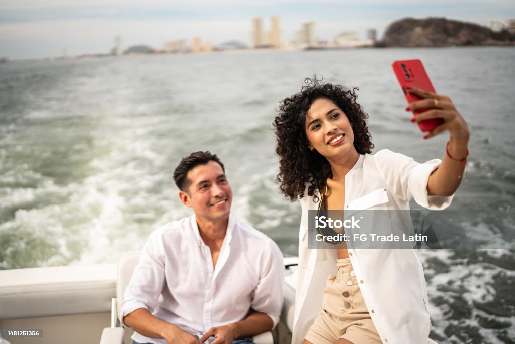 Friends taking a selfie or filming using mobile phone during a yacht trip Nautical Vessel Stock Photo