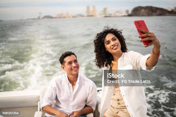 Friends Taking A Selfie Or Filming Using Mobile Phone During A Yacht Trip Stock Photo - Download Image Now