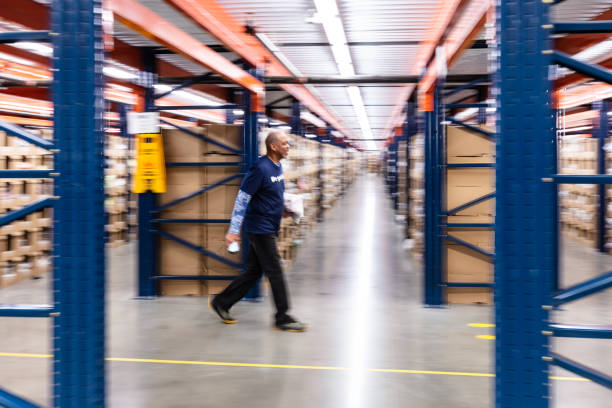 성숙한 아프리카계 미국인 남자가 주문 처리 센터에서 스캐너와 패키지를 들고 걷는 흐릿한 샷 - working retirement blurred motion distribution warehouse 뉴스 사진 이미지