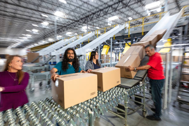 istock Blurry Still Of Diverse Group Of Workers Handling Boxes On an Expandable Conveyor In a Fulfillment Center 1481252909