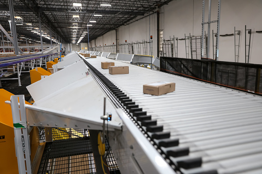 Shot of cardboard boxes on top of a conveyor belt in a fulfillment center.