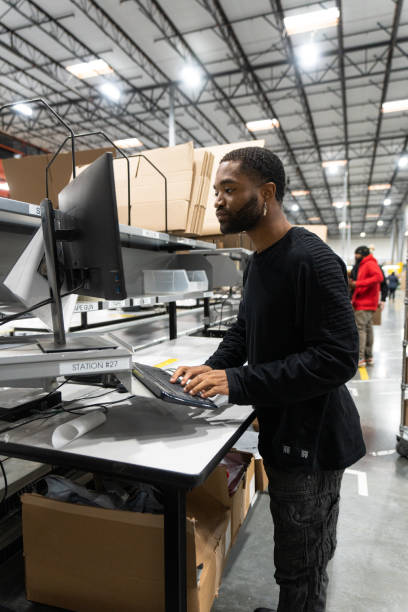 istock Young African American Man Working On a Computer In a Fulfillment Center 1481253008