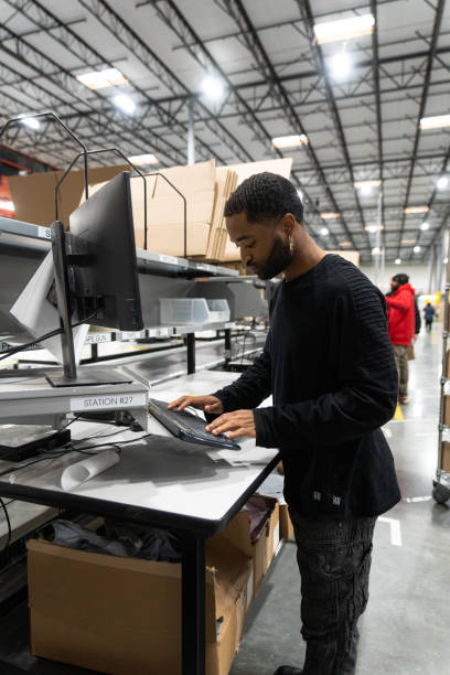 istock Young African American Man Typing On a Computer In a Fulfillment Center 1481253010