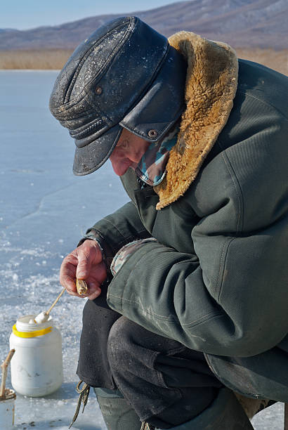 istock Old man on winter fishing 148125387