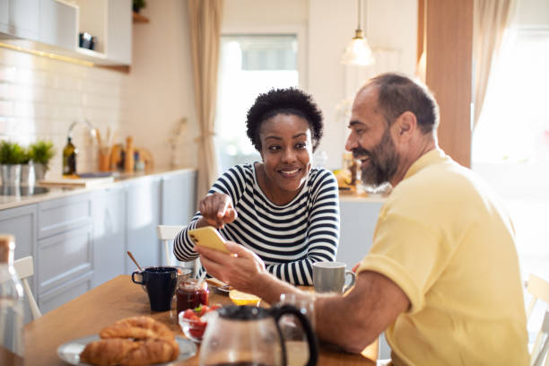 istock Mid adult couple using a smart phone while having breakfast 1481255764