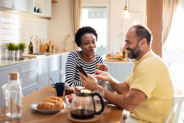 istock Mid adult couple using a smart phone while having breakfast 1481256036