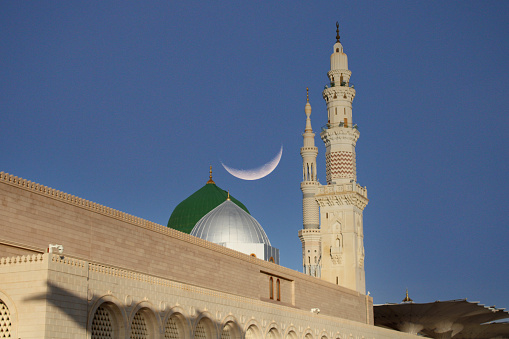 A mosque with a crescent moon in the sky .Masjid nabi of Medina. Green dome. Ramadan Kareem. Eid Mubarak