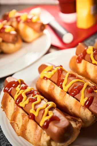 Freshly prepared hotdoags on a plate with red sauce and mustard