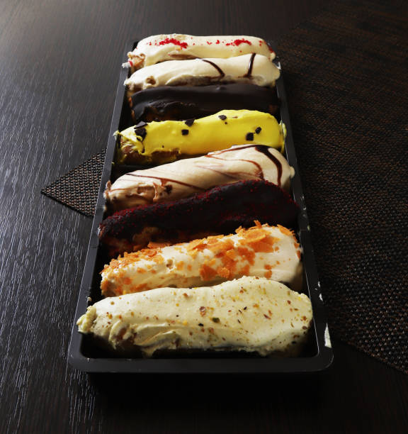 Classic French eclairs of oblong shape with various fillings and chocolate, mango, fruit creams on them. Close-up