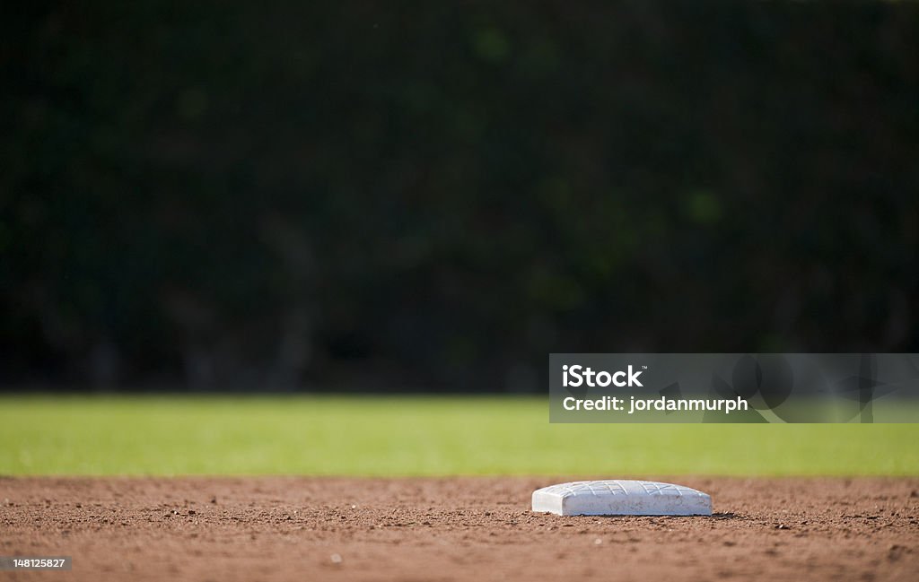 Low angle photo of an empty baseball base Second base and a dark outfield Baseball Diamond Stock Photo