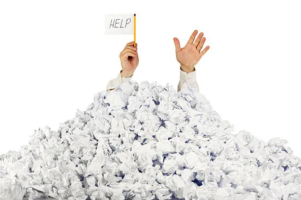 Photo of Person under crumpled pile of papers with  help sign